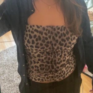 Leopardmönstrad bandeau tubtopp - Säljer en snygg bandeau tubtopp med leopardmönster i svart och beigebrun. Toppen är ärmlös och har en tight passform som sitter uppe utan axelband. Materialet är mjukt och stretchigt syntet🤎🐆