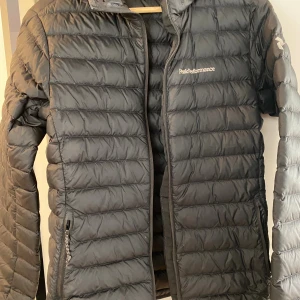 Svart jacka  Peak Performance - Snygg svart jacka, herr S, från Peak Performance med horisontella sömmar och diskret logga på bröstet. Jackan har dragkedja framtill och två sidofickor med dragkedja. 