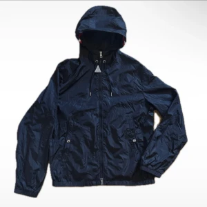 Mörkblå vindjacka från Moncler - Säljer min moncler windbreaker i färgen svart. Jackan är i ett fint skick. Köpte den begagnat så vet ej om den är äkta eller inte. Funkar när man lägger mobilen mot märket. Den är i storlek 4 och passar stor M liten L