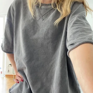 Oversized grå t-shirt från Zara - Säljer en oversized grå t-shirt från Zara med korta ärmar och ribbad rund halsringning. T-shirten har en avslappnad passform och är gjord i mjuk bomull, perfekt för en chill och enkel stil.
