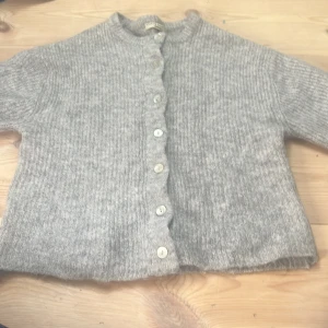 Grå stickad kofta från Gina Tricot - Mysig grå stickad kofta från Gina Tricot i storlek XS. Koftan har rund hals, ribbad struktur och knäpps med sju pärlemorknappar framtill. Perfekt för en chill höst- och vinterstil. Pris kan diskuteras💕