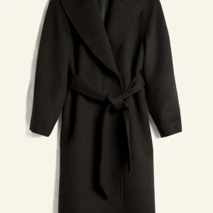 Svart lång kappa med bälte - Stilren svart kappa med bred krage och knytskärp i midjan. Lång modell med rak passform och långa ärmar, perfekt för kyliga dagar. Tillverkad i ett mjukt ullmaterial som ger en lyxig känsla och snygg siluett. Använd enstaka gånger, nästintill helt ny