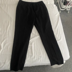 Svarta slim fit byxor från H&M - Svarta stilrena byxor från H&M i slim fit-modell med resår och dragsko i midjan. 