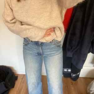 Blå broderade jeans från Monki - Säljer ett par ljusblå jeans från Monki med snyggt broderade blommor i grönt och vitt på fickorna bak och på framsidan. Inte jätte högmidjade och raka ben. Inga defekter. Byxorna är i storlek 27. 
