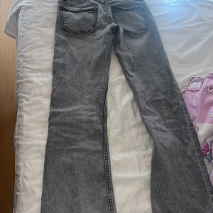 Grå jeans med stjärndetalj Gina Tricot - Grå jeans från Gina Tricot i storlek 152. Klassisk femficksmodell med rak passform och snygg stjärndetalj på bakfickan. Jeansen har knappgylf och är tillverkade i ett mjukt denimtyg som är skönt att bära hela dagen.