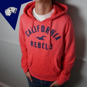 HOLLISTER HOODIE - Riktig fet Hollister hoodie i rosa/röd färg | Skick: 9/10 (solblekning och slitningar är från fabrik) | Strl: M | Modellen är 182 cm | Hör av dig vid intresse eller om du undrar någonting! 