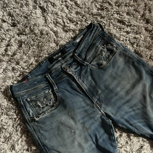 Replay Anbass Slim fit jeans - Säljer dessa Replay Jeans i modellen Anbass som har en slim passform. De är i ok skick har många slitningar och fläckar osäker på om fläckarna går bort. Jeansen är i storlek 31/32. Bara att skriva över frågor och funderingar.