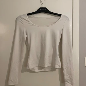 Vit långärmad topp med rund hals - Säljer en enkel och stilren vit långärmad topp från KappAhl. Toppen har rundad halsringning och sitter figurnära på kroppen. Perfekt att matcha med jeans eller kjol för en clean look. Materialet är mjukt och stretchigt, vilket gör den superbekväm.