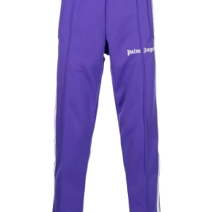 Palm Angels lila trackpants - Snygga lila trackpants från Palm Angels med vita revärer längs sidorna och logga tryckt på låret. Byxorna har en relaxed passform och är tillverkade i ett mjukt syntetmaterial som ger en sportig vibe. Perfekta för dig som gillar streetwear och vill sticka ut. Fraktar runt hela Sverige