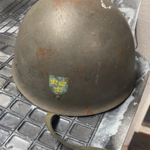 Ovanlig Grön militär hjälm  - Säljer en grön, rundad militär hjälm med slät yta och diskreta nitar på sidorna. Perfekt för dig som gillar army-vibe eller vill sticka ut med en unik accessoar. Passar till cosplay eller som cool detalj i garderoben. Unik hjälm 