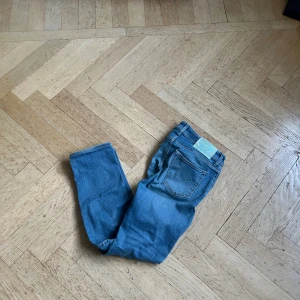 Jacob Cohen ljusblå jeans straight fit - Snygga ljusblå jeans från Jacob Cohen med raka ben och klassisk femficksdesign. Jeansen har turkosa detaljer på knappar och patch, samt synliga sömmar. Materialet är mjukt denim och insidan har ett mönstrat tyg vid fickorna. Perfekt för dig som gillar stilrena jeans med unika detaljer.
