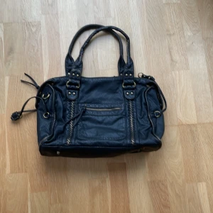 Svart väska - En svart väska i skinnimitation. Totalt tre fickor på insidan, en som man kan stänga, och två fickor på utsidan. Man får plats med en dator. Extra axelrem följer med. Namn på hemsidan är Anma Citybag.