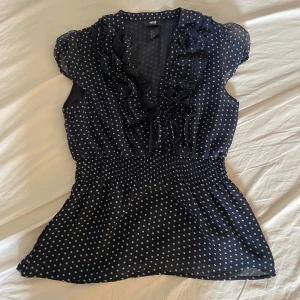 Prickig blus med volang från H&M - Figursydd prickig blus med volang från H&M strl XS