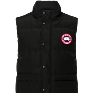 Svart dunväst från Canada Goose - Svart dunväst från Canada Goose med hög krage och klassisk logotyp på bröstet. Västen har tryckknappar framtill och två stora fickor. Perfekt för lager-på-lager och håller dig varm under kyliga dagar.