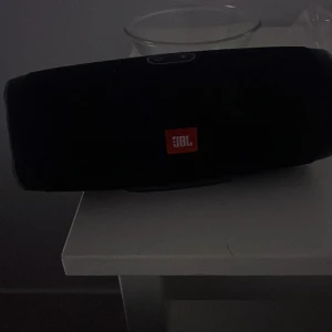 JBL Charge 3 Bluetooth-högtalare - Kraftfull JBL Charge 3 bärbar Bluetooth-högtalare med tydligt ljud och djup bas. Vattentålig design, perfekt för både inomhus och utomhus. Högtalaren ser ut att vara i gott skick utan synliga skador eller slitage.