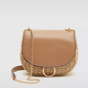 Beige axelväska från Mango med kedja - Snygg beige axelväska från H&M med flätad kropp och lock i brunt skinnimitation. Väskan har guldfärgad kedjerem och rund metallring framtill. Perfekt storlek för det viktigaste och ger en chill boho-vibe till din outfit.