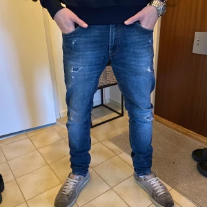 Jack and Jones slim fit jeans med slitningar - Säljer ett par sjukt feta Jack and Jones jeans med snygga slitningar. Jeansen är i använt men ändå bra skick. Jeansen har i en av slitningarna ett litet hål men som knappt syns. Modellen är 177cm och väger 61 kg. (Nypris ca 800kr) mitt pris 399