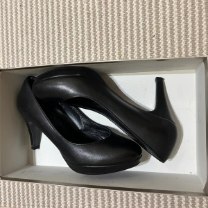 Svarta pumpsi skinn  med rund tå från Billi Bi  Stl 37  - Klassiska svarta pumps från Alibi med rund tå och låg klack. Skorna har en stilren design i syntetmaterial och en diskret plattform framtill. Perfekta för dig som gillar en enkel och elegant look. Klack 8 cm hög , använda en enda gång 