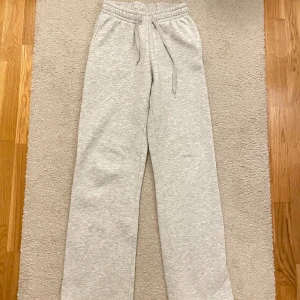 Grå mjukisbyxor med snörning - Säljer dessa trendiga mjukisbyxor från Gina. De är använda o lite små noppiga men fof fina! Storlek xs men passar också mindre eller större beroende på hur man vill att de ska sitta. Säljer då de börjar bli för små.☺️Ljusgrå mjukisbyxor med rak passform och elastisk midja med snörning. Byxorna är tillverkade i mjukt bomullsmaterial och har en avslappnad look, perfekta för chill dagar. Klassisk design utan synliga loggor eller detaljer.