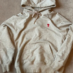 Grå hoodie från Ami Paris - Nice hoodie from ami paris. Its in good condition only problem is that the wrist part on both hands opened a little but that can be easily fixed. Bought from vinted a while a go so im not sure about the authenticity.
