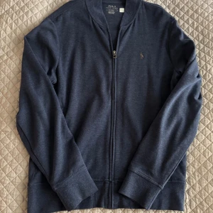 Blå kofta från Polo Ralph Lauren - Schysst Mörkblå kofta med dragkedja från Polo Ralph Lauren, i ett riktigt skönt material. Storlek M kan funka för S. Pris är förhandlingsbart bara att kontakta vid frågor eller funderingar.