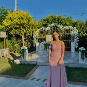 Ljusrosa offshoulder balklänning - Säljer en elegant ljusrosa långklänning med offshoulder och draperad överdel. Klänningen har figurnära passform upptill och faller snyggt i ett långt, svepande tyg. Perfekt för bal eller fest. Materialet känns lätt och flowy, med dragkedja i ryggen.