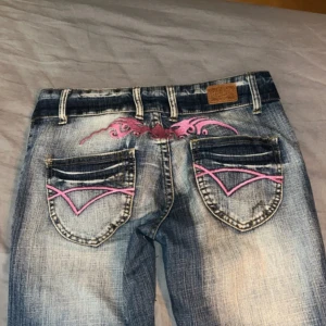 Blå bootcut jeans Crazy Age med rosa detaljer - Snygga blå bootcut jeans från Crazy Age med rosa broderade detaljer på bakfickorna och framtill. Jeansen har låg midja. I storlek 26, skriv gärna för måtten💞