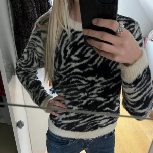 Zebramönstrad stickad tröja - Säljer en supermjuk stickad, zebramönstrad tröja från Mango i svart och vitt. Tröjan är som ni ser lite lurvig, och så himla skön! Den är även lite tjockare så perfekt nu när det blivit kallare. Storlek m men liten i storlek och passar som xs/s och tröjan är knappt använd så i nyskick utan defekter, nypris 419!🩶