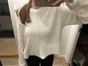 Vit oversized stickad tröja NA-KD - Säljer en vit stickad tröja med oversized passform och långa ärmar. Tröjan har en rund halsringning och en snygg söm som går vertikalt framtill. Mjuk och skön, perfekt för chill dagar. Passar dig som gillar en loose och avslappnad stil.