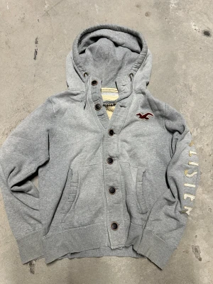 Vintage Hollister kofta med knappar - Extremt eftertraktad och sällsynt vintage  Hollister hoodie med knappar! Grymt skick, inga defekter - ser exakt ut som på bild! Storlek L passar M med!. Skriv vid frågor!💬
