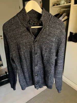 Mörkblå kofta från Massimo Dutti - Snygg mörkgrå kofta från Massimo Dutti i storlek L. Koftan är stickad i ullblandning och har en grov ribbad krage, knappar hela vägen och långärmad design. Perfekt för kyliga dagar och har en riktigt chill vibe.