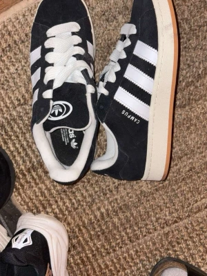 Adidas Campus svarta sneakers stl 43 1/3 - Svarta Adidas Campus sneakers storlek 43 1/3. Knappt använda då de inte passa mina fötter. Använda ca 2 gånger i 20 minuter.