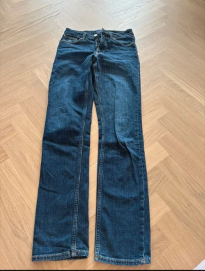 Slim jeans från GANT i mörkblå denim - Snygga mörkblå jeans från GANT med klassisk femficksdesign och kontrastsömmar. Modellen är slim fit och har dragkedja i gylfen samt GANT-logga på fickan. Perfekt passform för dig som gillar stilrena och tidlösa jeans.