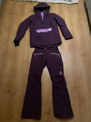 skidset wearcolour - Säljer ett par mörklila täckbyxor från Dope Snow med vita dragkedjor och snygga läderdetaljer på fickorna. Byxorna har en rak passform och är perfekta för vinterns alla äventyr. Matchande jacka finns också om du vill köra full look!