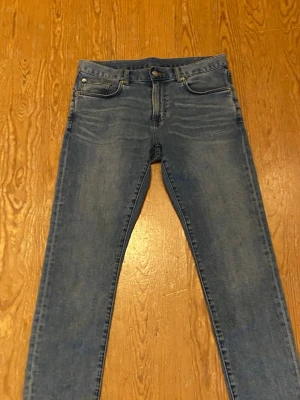 Blå slim fit jeans från East West - Snygga blå slim fit jeans från East West med klassisk femficksdesign. Jeansen har en lätt tvättad look och är tillverkade i en mix av bomull, polyester och elastan för skön stretch. Perfekta för dig som gillar en smalare passform och stilren look.