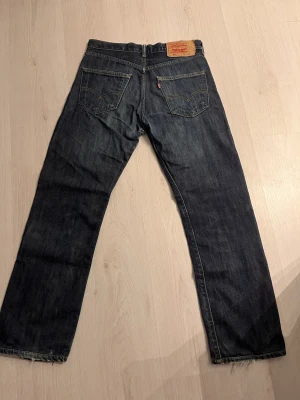 Levi's 501 mörkblå jeans W31 L32 - Klassiska Levi's 501 jeans i mörkblå denim med raka ben och femficksmodell. Ikonisk läderpatch bak i midjan. Återkom vid frågor eller funderingar!