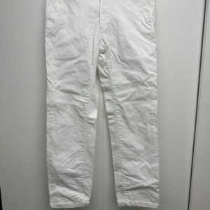 Vita kostymbyxor från Dressmann 31/32 - Snygga vita kostymbyxor från Dressmann i regular fit. Klassisk rak modell med fickor i sidorna och diskret knappstängning. Perfekta för dig som vill ha en clean och stilren look. Materialet är mjukt och bekvämt bomull.