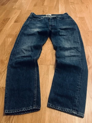 Mörkblå jeans från Acne Studios - Snygga mörkblå jeans från Acne Studios med raka ben och klassisk femficksdesign. Jeansen har knäppning med fyra metallknappar med Acne Studios-logga och är tillverkade i robust denim. Perfekta för dig som gillar en tidlös och clean look.