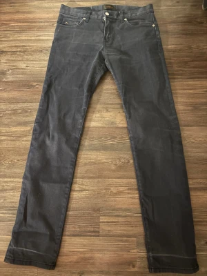 Svarta slim jeans J.Lindeberg Jay - Snygga svarta jeans från J.Lindeberg, modell Jay med slim fit och midwaist. Klassisk femficksdesign, diskret logga på myntfickan och silverfärgade knappar. Jeansen är tillverkade i ett mjukt bomullsmaterial med lite stretch för extra komfort.