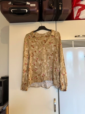 Odd molly blus  - Säljer en superfin blus i guld färg men ett blommig mönster. Från märket Odd Molly. Storlek 2 som enligt deras storleksguide motsvarar en M. Fin men det har tyvärr tråddraningar. 