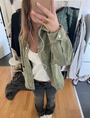 Grön trendig jeansjacka från Zara - Snygg ljusgrön jeansjacka från Zara med klassisk krage och stora fickor framtill. Jackan har raka, långa ärmar och knäpps med silvriga knappar. Perfekt att slänga över en t-shirt för en chill och trendig look.