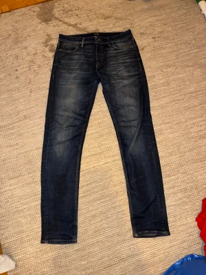 Mörkblå jeans från Jack & Jones 33/36 - Snygga mörkblå jeans från Jack & Jones. Modellen har raka ben och normal passform, tillverkade i slitstarkt bomullsmaterial. Perfekt för dig som gillar stilrena och grisch jeans. 33/36 men de är kortare i modellen så passar 33-34 i längd som bäst.
