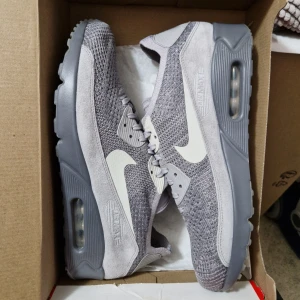 Oanvända Nike Air Max 90 Flyknit EU44.5 - Helt nya i original låda. Innermått 28.5 cm. Resellpris ca 2600 kr. Mitt sista pris 1800kr Lätta skor med stickad överdel som andas bra. Skickar spårbart och försäkrat. OBS! Inga byten eller returer. Skambud undanbedes! 