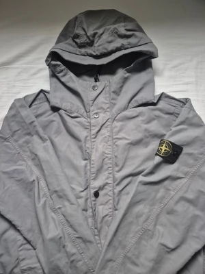 Grå vindjacka från Stone Island - Säljer en grå vindjacka från Stone Island med klassisk patch på vänster ärm, design som funkar till streetwear.Den har nått litet håll. Den är i bra skick och har en väldigt bra passform, och har ni frågar skriv dm📌  [Nordic Resell]