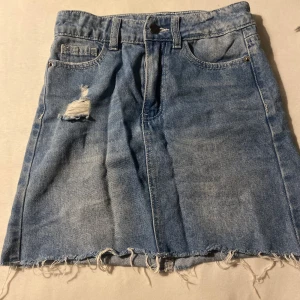 Blå jeanskjol från UNIQ med sliten kant - Säljer en blå jeanskjol från UNIQ ,skriv om ni har frågor 