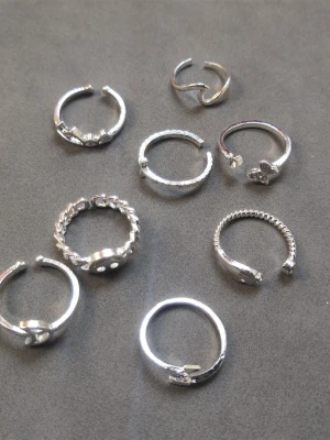 8 st ringar  - Säljer ett set med 8 olika silverfärgade ringar med olika former och mönster. Materialet är alloy. (603)