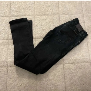 Svarta Replay jeans w29/34 - Säljer ett par svarta Replay jeans med klassisk femficksdesign och snyggt tapered snitt. Jeansen har en mörk tvätt och är tillverkade i mjukt jeansmaterial med stretch för extra komfort. Perfekta för dig som gillar stilrena och moderna jeans.