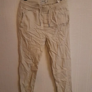 Beige linnebyxor från Solid XS - Snygga beige linnebyxor från Solid i storlek XS. Byxorna har elastisk midja med snörning, sidofickor och bakfickor. Perfekt för chill dagar och har en relaxed passform med tapered ben. Luftigt material som känns skönt mot huden. 