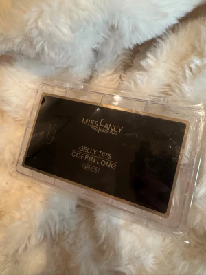 Miss Fancy Gelly Tips Coffin Long - Säljer ett set med 500 st Gelly Tips Coffin Long från Miss Fancy Professional. Nageltipsen är transparenta och har en snygg coffin-form som ger en trendig look. Perfekt för dig som vill fixa egna naglar hemma med salongskänsla. Kommer i en praktisk plastask.