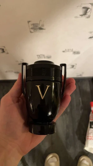 Invictus parfym 100ml - Stilren och cool parfymflaska i svart med ett stort V på framsidan. Perfekt för dig som vill sticka ut med en modern och sportig look. Märket Paco Rabanne syns på flaskans ovansida. 